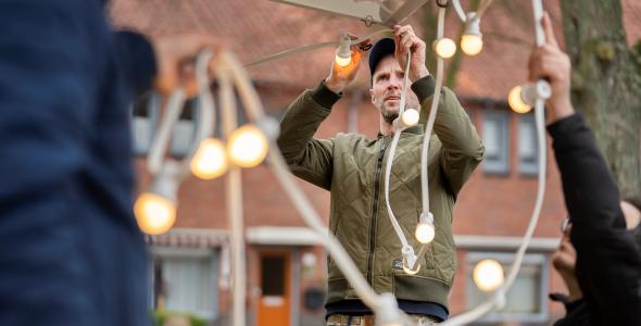 Medewerker van WIJeindhoven hangt versiering op voor buurtfeest